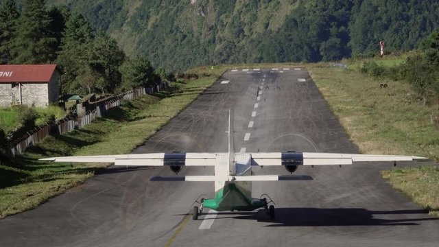 Small airplane take off from Tenzing-Hillary Airport in Lukla. The airport in Lukla is the most dangerous airport in the world. He is on high in the mountains. From here begins the track to Everest