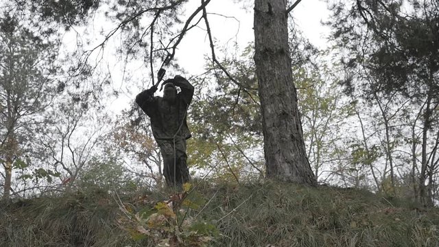 Male paintballer doing somersault in the forest