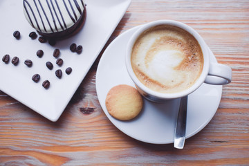 Un café con leche y un dulce sobre una mesa de madera