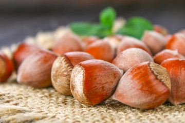 Walnut hazelnuts on a burlap on a brown wooden table.
