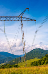 high voltage power lines tower in Carpathian mountains. lovely green energy industry concept. beautiful landscape in autumn with blue sky and some clouds