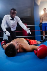 Male boxer looking while referee counting by athlete