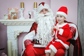 Image of happy Santa Claus and boy near the decorated Christmas tree.