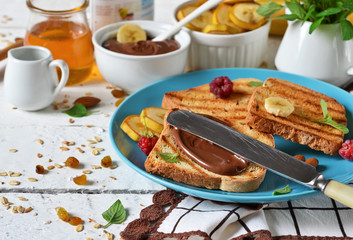 Good morning - toast with walnut, chocolate paste, banana and honey. White food background.