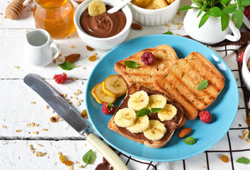 Good morning - toast with walnut, chocolate paste, banana and honey. White food background.