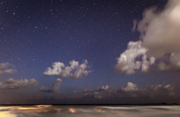 The night star sky over the ocean with the broken-off running clouds and a luminescence in the...