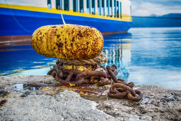 Thick boat ropes tied to an old rusty bollard 