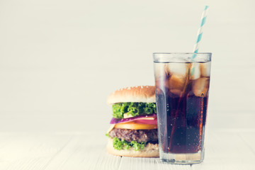 Cold glass of cola and big burger