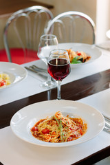 Italian traditional pasta with tomatoes and seafood on restaurant table.