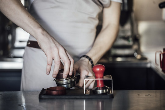 Hands of unrecognisable barman using espresso filter.