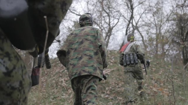 Paintball players walking through the forest in slow motion