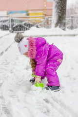 Little kid girl shoveling snow on home drive way.