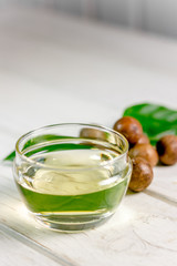 Natural and organic macadamia oil on a white wooden table.