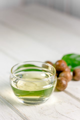 Natural and organic macadamia oil on a white wooden table.