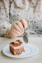 Woman eating small cake in a restaurant.