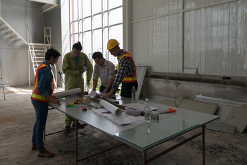 Engineer group asia and worker meeting, discussion with construction on site work in friendly atmosphere joking and having fun during working process.