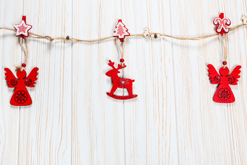 Christmas wooden red toys in the shape of a deer and an angelic rope on a white wooden background....