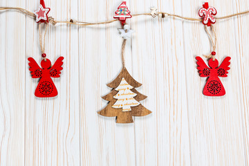 Christmas wooden toys are hung on a rope on a white wooden background. Beautiful festive greeting card with free space