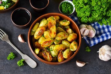 Young fried potatoes with garlic and dill on a black background