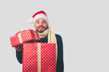 Handsome man in a Christmas hat holding gifts on white background