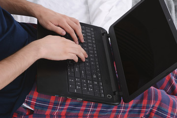 Naklejka na ściany i meble Man using laptop in bed.