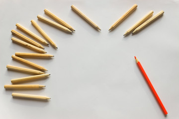 Red pencil standing out from crowd of plenty identical  pencils on table. Leadership, uniqueness, independence, initiative, strategy, dissent, think different, business success concept.