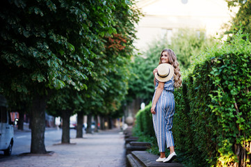 Obraz premium Portrait of a fabulous young woman in striped overall walking on the barrier in the park.