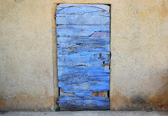 Old blue wooden door embedded in yellow wall