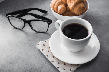 hot coffee cup with tasty croissant on stone table