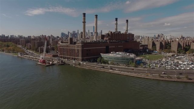 Aerial shot of a power station in New York City. Camera slowly is going up filming Power Station and Downtown of Manhattan.