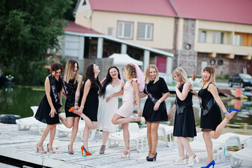 Fototapeta premium Group of 8 girls wear on black and 2 brides at hen party at pier on beach side.