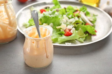 Glass jar with ranch salad dressing on table
