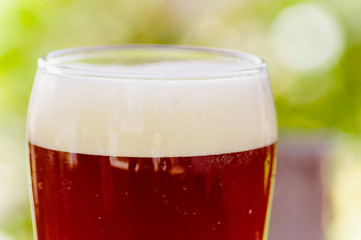 Close up of glass of beer with a blurred nature background