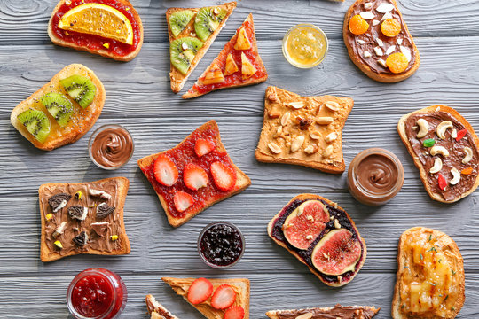 Toasts with various delicious toppings on wooden background