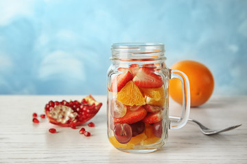 Delicious fruit salad in mason jar on table