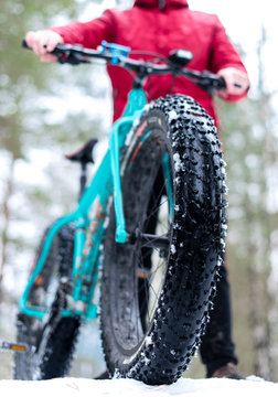 A big wheel from the bike. Fatbike in the winter in the hands of a man in a red jacket
