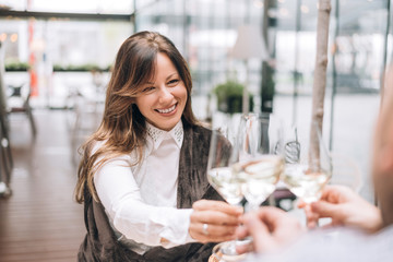 Brunette woman clinking glasses with friends in cafe.