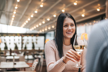 Woman on date in cafe clinking glasses.