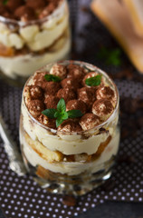 Classic tiramisu in a glass jar on the background chermon