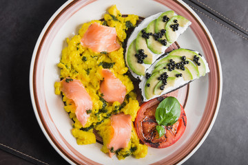 Scramble with avocado, tomatoes and pieces of salmon