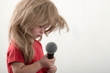 Happy little boy in smart clothes is singing a song with a microphone at home. Preparing for the Christmas Karaoke