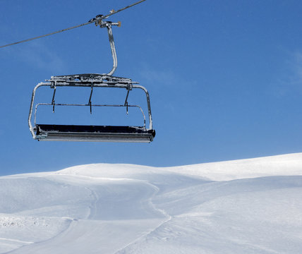 Ski slope, chair-lift on ski resort and blue sky with falling snow