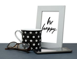 Be happy. Handwritten inscription in the frame. Modern calligraphy. Coffee Cup, mobile phone