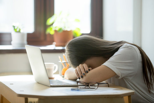 Tired young woman falling asleep at desk after overwork. Exhausted sleep deprived stressed female manager lying on table and sleeping after hard working day, no energy left
