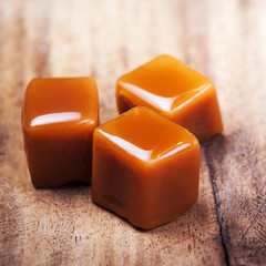 Homemade salted caramel pieces  on wooden  background. Golden Butterscotch toffee candy caramels...