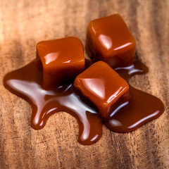 Organic caramel candies and caramel sauce on wooden table, Golden Butterscotch toffee caramels.