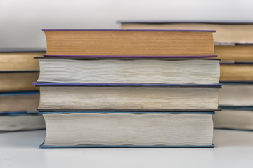 On a white table are collected paper books. A symbol of knowledge and wisdom.