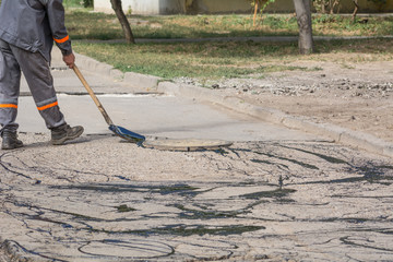 Road repair. Work details, workers pour resin road surface to cover the asphalt