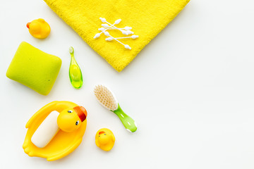 Baby bath set with yellow rubber duck. Soap, sponge, brushes, towel on white background top view copyspace