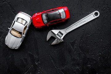 Car repair concept. Wrench near car toys on black background top view copyspace